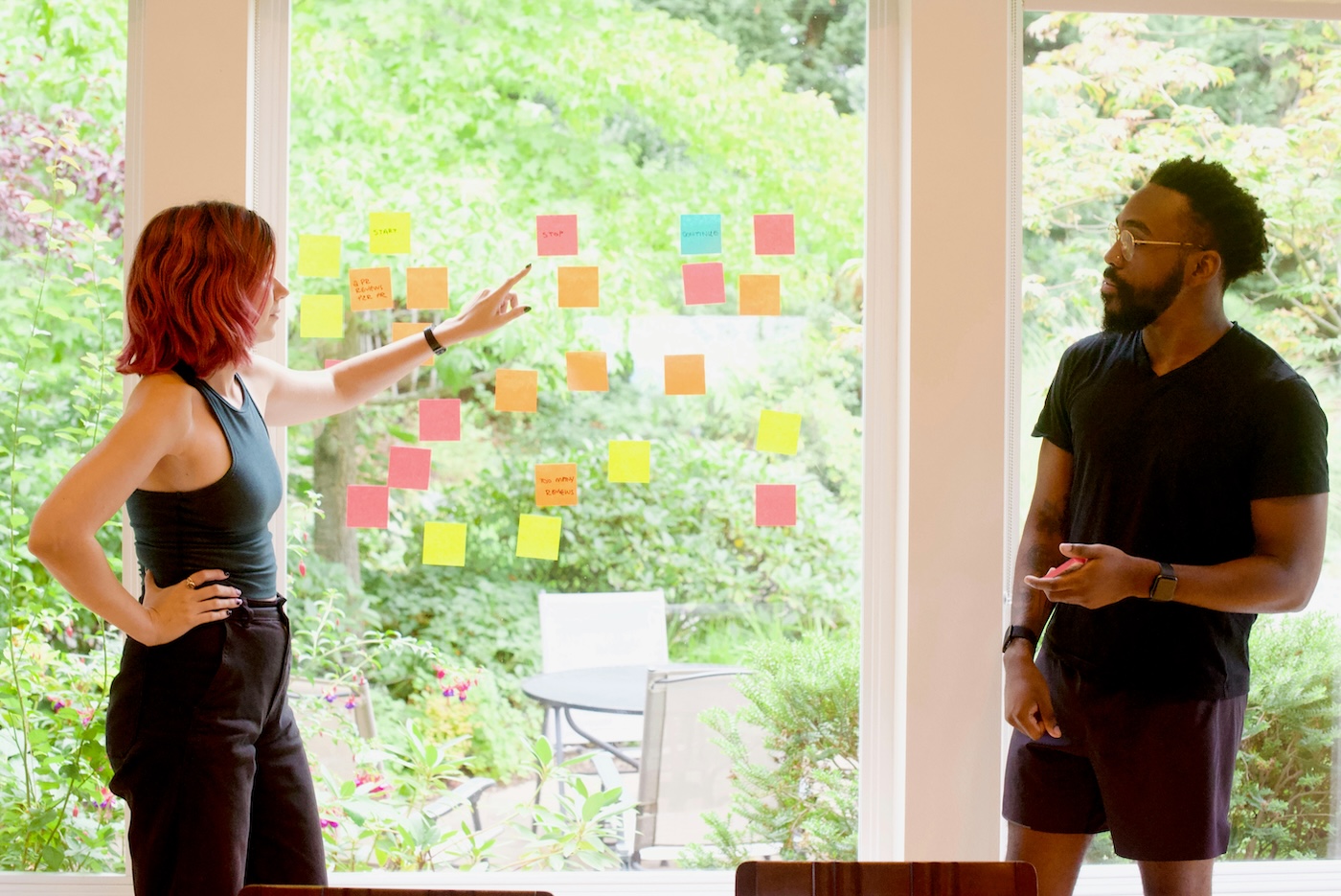 Two people presenting. Post-it notes against window.